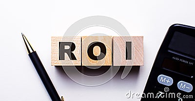 ROI Return on investment written on wooden cubes between calculator and pen on light background. Investment concept Stock Photo