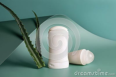 Roll on antiperspirant and solid deodorant near two fresh aloe leaves against against teal blue wavy baskground. Natural herbal Stock Photo