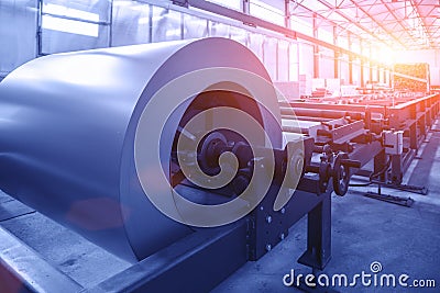 Roll of galvanized steel sheet at cutting machine in worksop conveyor line as abstract industrial equipment background, toned Stock Photo