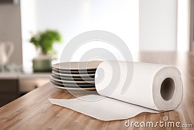 Roll of paper towels with plates on kitchen table Stock Photo