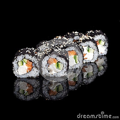 Roll Smoked California with cucumber, avocado, eel and black tobiko caviar on black with reflection. Close up. Japanese Stock Photo