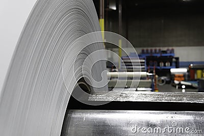 Roll of Steel on factory decoiler machine. used to make roofing sheets. Metal roll being uncoiled Stock Photo