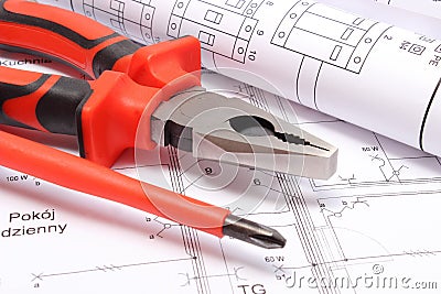 Rolled electrical diagrams and work tools on construction drawing of house Stock Photo