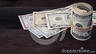 Rolled hundred dollar on background series American money 5,10, 20, 50, new 100 dollar bill on brown wooden background. Stock Photo