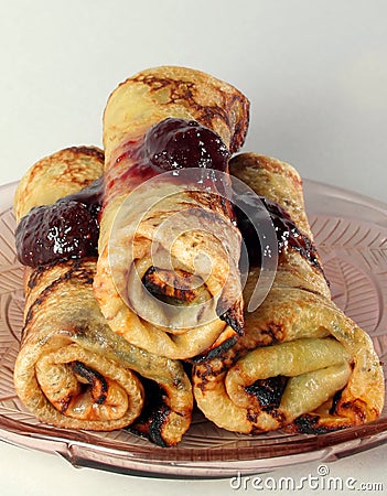 Rolled pancakes with strawberry jam on a glass plate Stock Photo