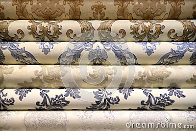 Rolled up rolls of vinyl wallpaper. Different textures and colors, as background White wallpaper with beige, purple Stock Photo