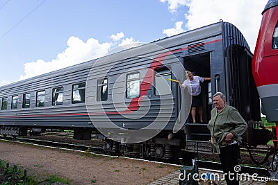 With a rolled-up yellow flag, the conductor informs the driver that there are no obstacles to the departure of the passenger train Editorial Stock Photo