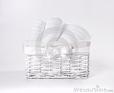 Rolled white soft terry towels in the basket against a white backdrop. Striped towels in a white basket in front of a white Stock Photo