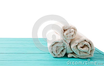 Rolled white towels on blue wooden table isolated on white background. Copy space and top view. Bathroom objects for shower body Stock Photo