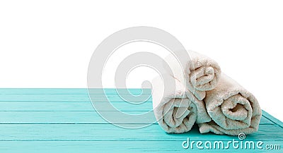 Rolled white towels on blue wooden table isolated on white background. Copy space and top view. Bathroom objects for shower body Stock Photo