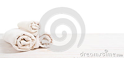 Rolled white towels on white wooden table on white background. Copy space and top view. Bathroom objects for shower body Stock Photo