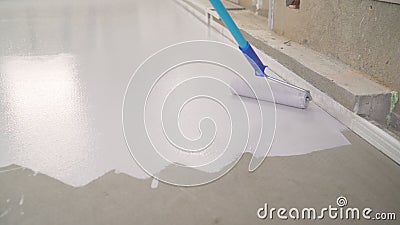 Contract painter painting garage floor to speed up selling of home. Rolling Epoxy Paint on Concrete Floor. Roller with concrete Stock Photo