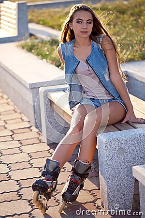 Roller girl wearing jeans sitting on bench Stock Photo