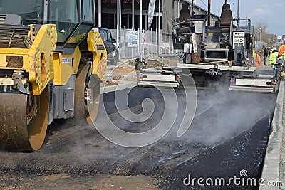 Roller machine compressing the asphalt behind the paver Editorial Stock Photo