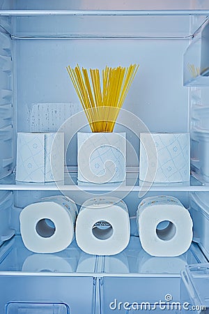 Rolls of toilet paper and spaghetti on shelves in fridge as symbol of hysteria Stock Photo