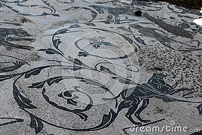 Roman mosaic with small black and white stones tiles representing a floreal decoration with animals. Detail of a mosaic in Stock Photo
