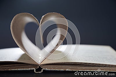 A Romance Novel. Open book close. The pages are arranged in a heart shape on a gray background in a blur. Photo with Stock Photo