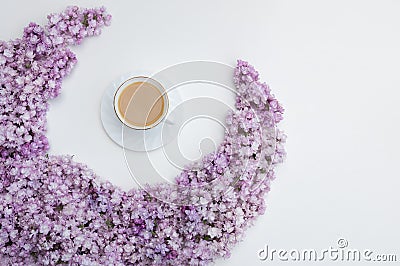 Romantic background with a cup of coffee, lilac flowers on a white table. Top view, place for text Stock Photo