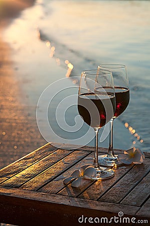 Romantic beach scene: two glasses of red wine at sunset near water Stock Photo