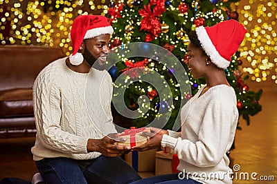 Romantic black couple exchanging presents near Christmas tree Stock Photo