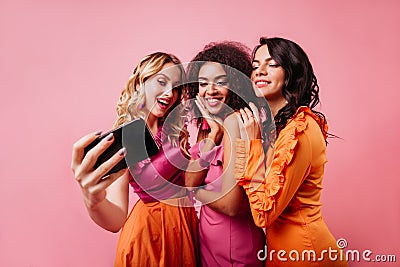 Romantic blonde girl making selfie with friends. Pretty ladies posing on pink background Stock Photo