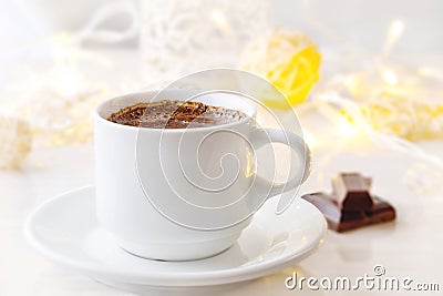 Romantic breakfast. A cup of black coffee with chocolate on a background of glowing lanterns. Stock Photo