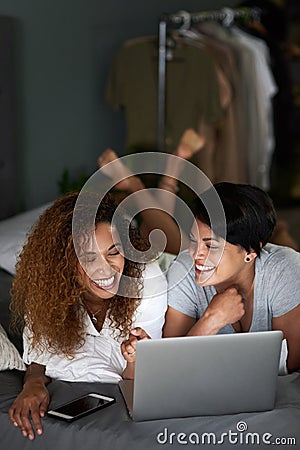 A romantic comedy is always a winner with us. a young couple using a laptop while lying on their bed. Stock Photo