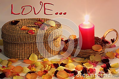 Romantic composition. Love. Wicker basket and braided candle and rose petals around Stock Photo