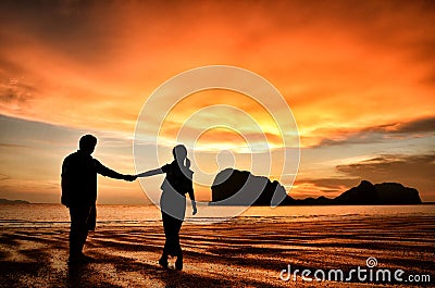 Romantic couple holding hands at sunset on beach Stock Photo