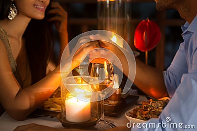 Romantic couple holding hands together over candlelight Stock Photo