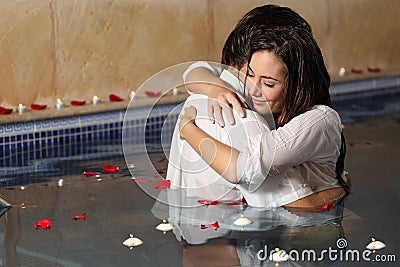Romantic couple hugging in a pool with candles and rose petals Stock Photo