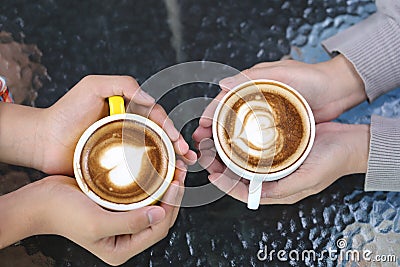 Romantic couple in love hand holding two cups of latte art with pattern the heart on table in coffee shop Stock Photo