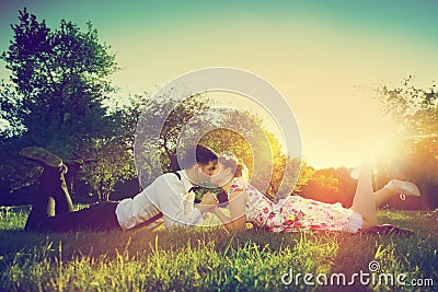 Romantic couple in love kissing while lying on grass. Vintage Stock Photo