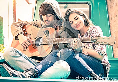 Romantic couple of lovers playing guitar on vintage minicar Stock Photo