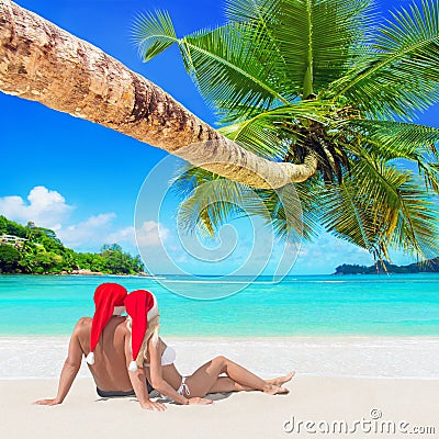 Romantic couple in red Christmas Santa hats sunbathe at tropical palm sandy island beach Stock Photo