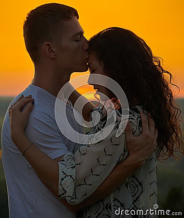 Romantic couple at sunset on outdoor, beautiful landscape and bright yellow sky, love tenderness concept, young adult people Stock Photo