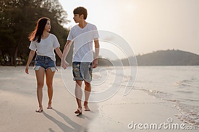 Romantic couple walking holding hands each other while at beach at sunrise, plan life insurance at future concept. Stock Photo