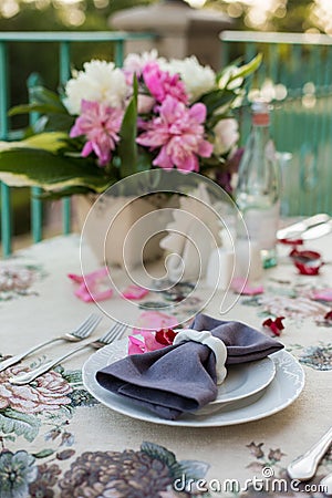 Romantic decor of the festive table in the restaurant with candles, flowers, rose petals Stock Photo