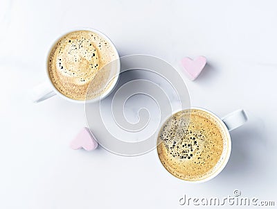 Romantic desk top with two cups of coffee and pink heart shaped marshmallows. Top view. Stock Photo