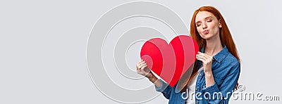 Romantic dreamy cute redhead teenager dreaming about giving boyfriend big red heart card to show her affection and love Stock Photo