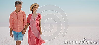 Romantic elegant couple on honeymoon vacation, walking by white salty coast Stock Photo