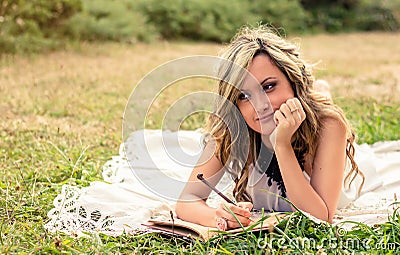 Romantic girl writing in a diary lying down Stock Photo