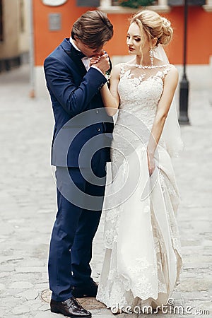 Romantic groom kissing hand of beautiful happy bride outdoors, newlywed couple portrait Stock Photo