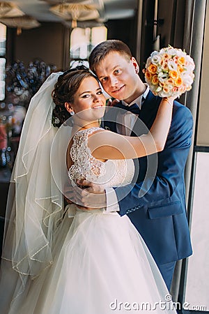Romantic happy couple, groom embracing his bride near window closeup Stock Photo