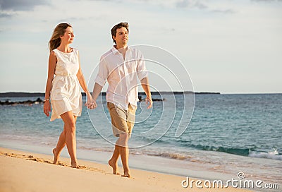 Romantic happy couple walking on beach at sunset Stock Photo