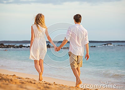 Romantic happy couple walking on beach at sunset Stock Photo