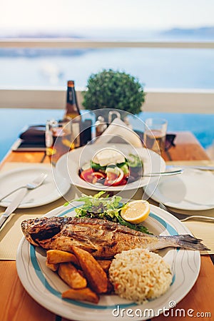 Romantic honeymoon dinner for two on Santorini island, Greece with seaside, volcano view. Greek salad and seafood Stock Photo