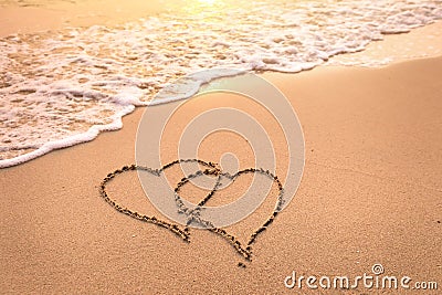 Romantic honeymoon holiday or Valentine`s day on the beach concept with two hearts drawn on the sand, tropical getaway for couple Stock Photo