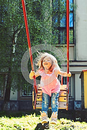 Romantic little girl on the swing, sweet dreams. childhood daydream. freedom. Playground in park. Small kid playing in Stock Photo