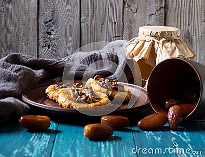 Romantic morning still life, in a rustic style with cookies, a glass jar of honey and scattered dates on a turquoise wooden Stock Photo